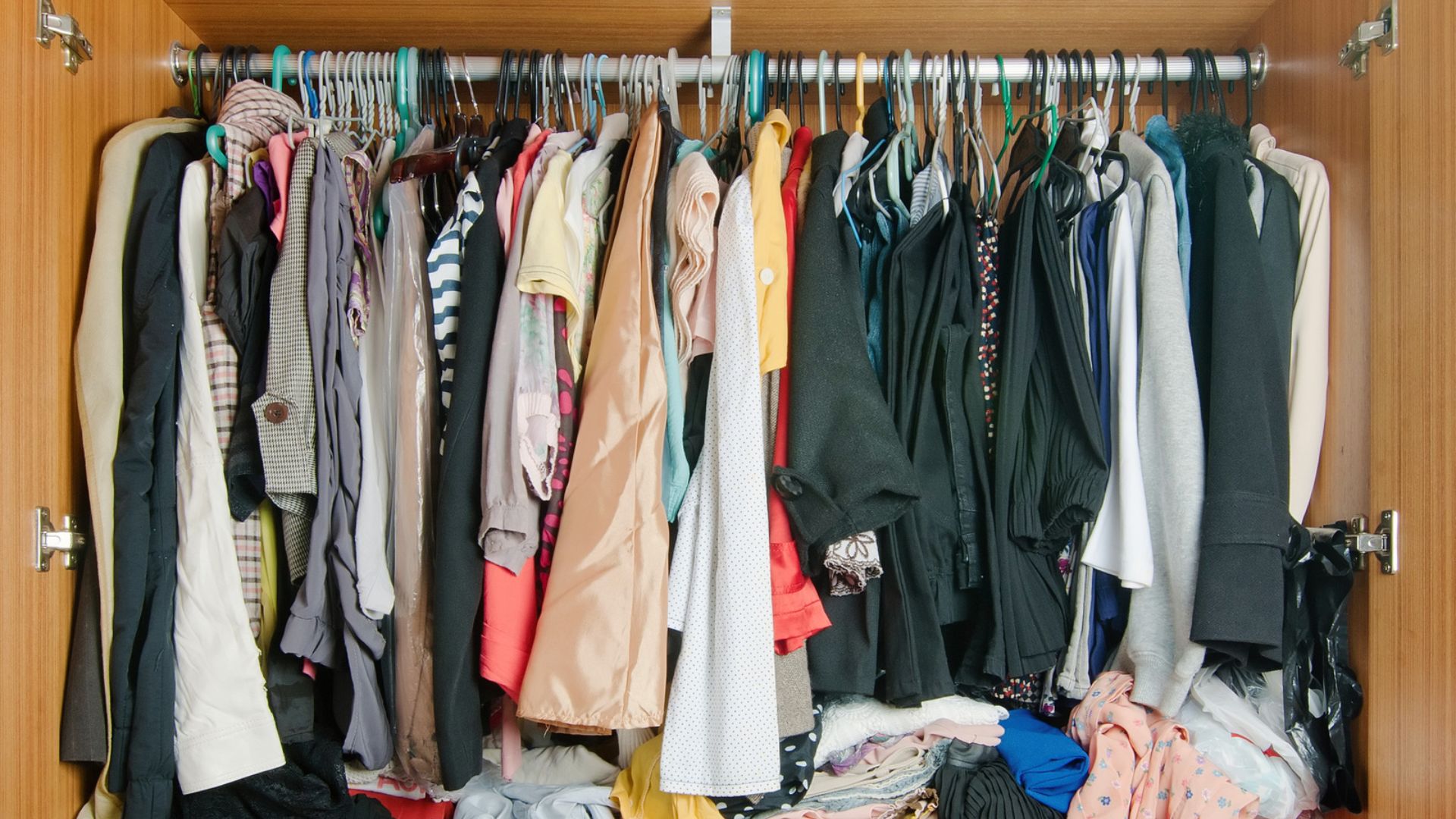Wooden wardrobe interior showing a single closet rod mounted near the top at standard height.