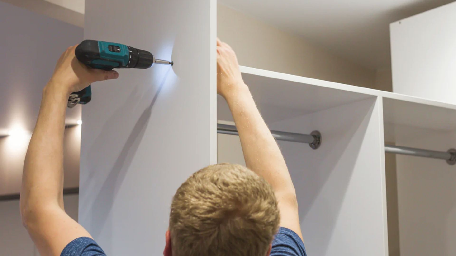 Person drilling into a white closet wall to install a mounting plate while a red level ensures alignment.