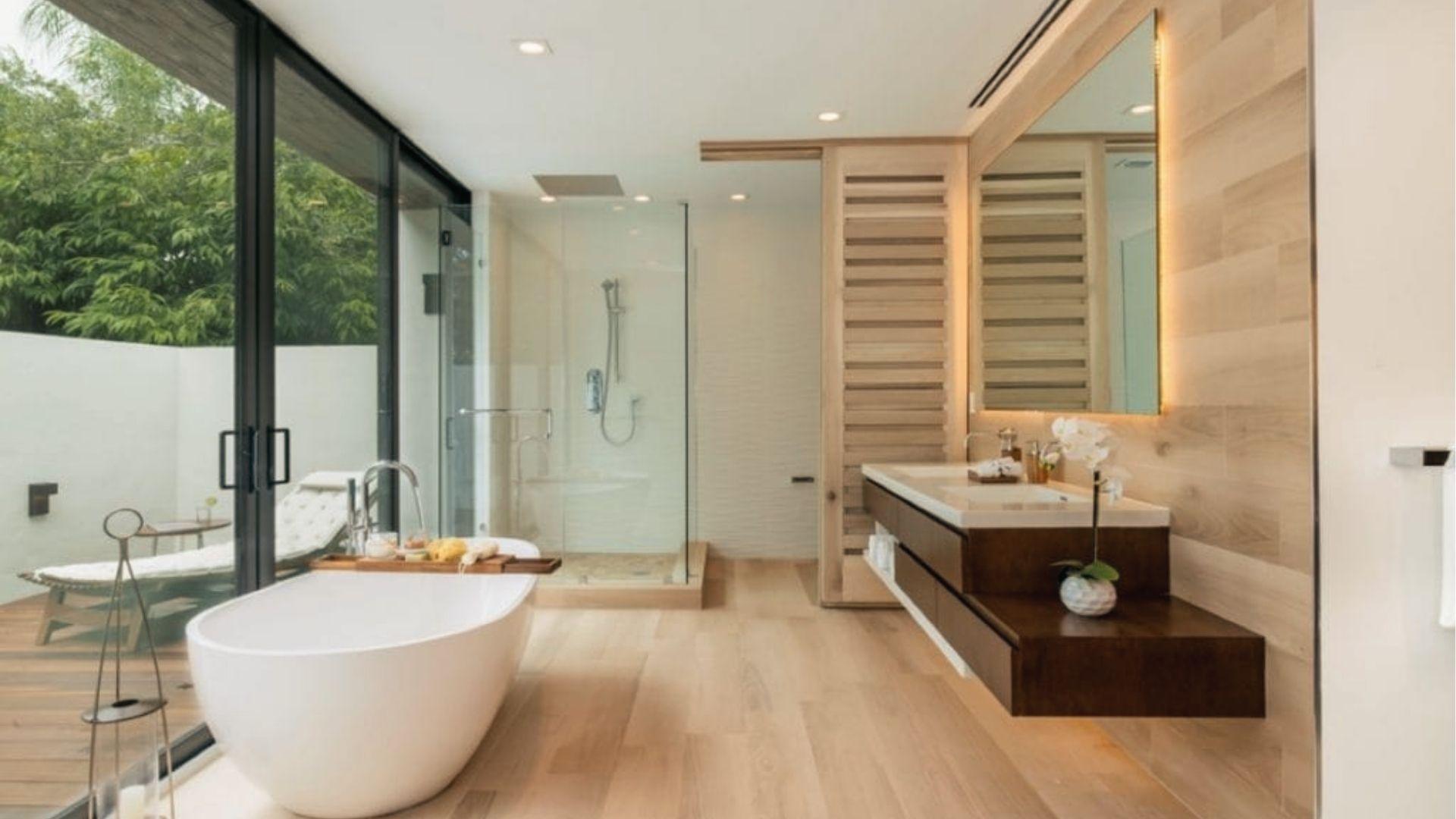 Open-concept bathroom closet combo featuring dual vanities, freestanding tub, and glass shower.