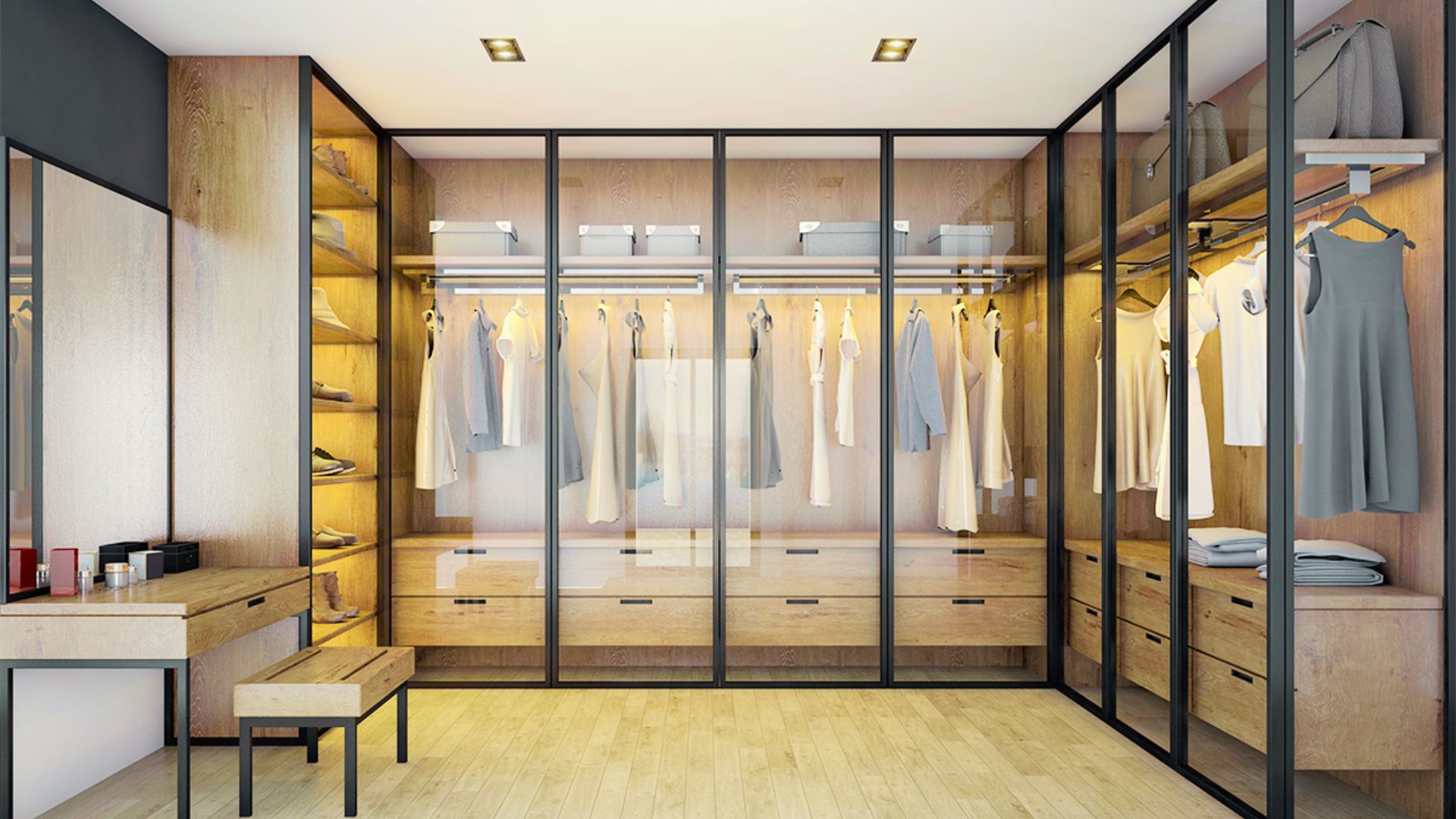 U-shaped glass door wardrobe with black frames, LED lights, wood drawers, bench, and vanity