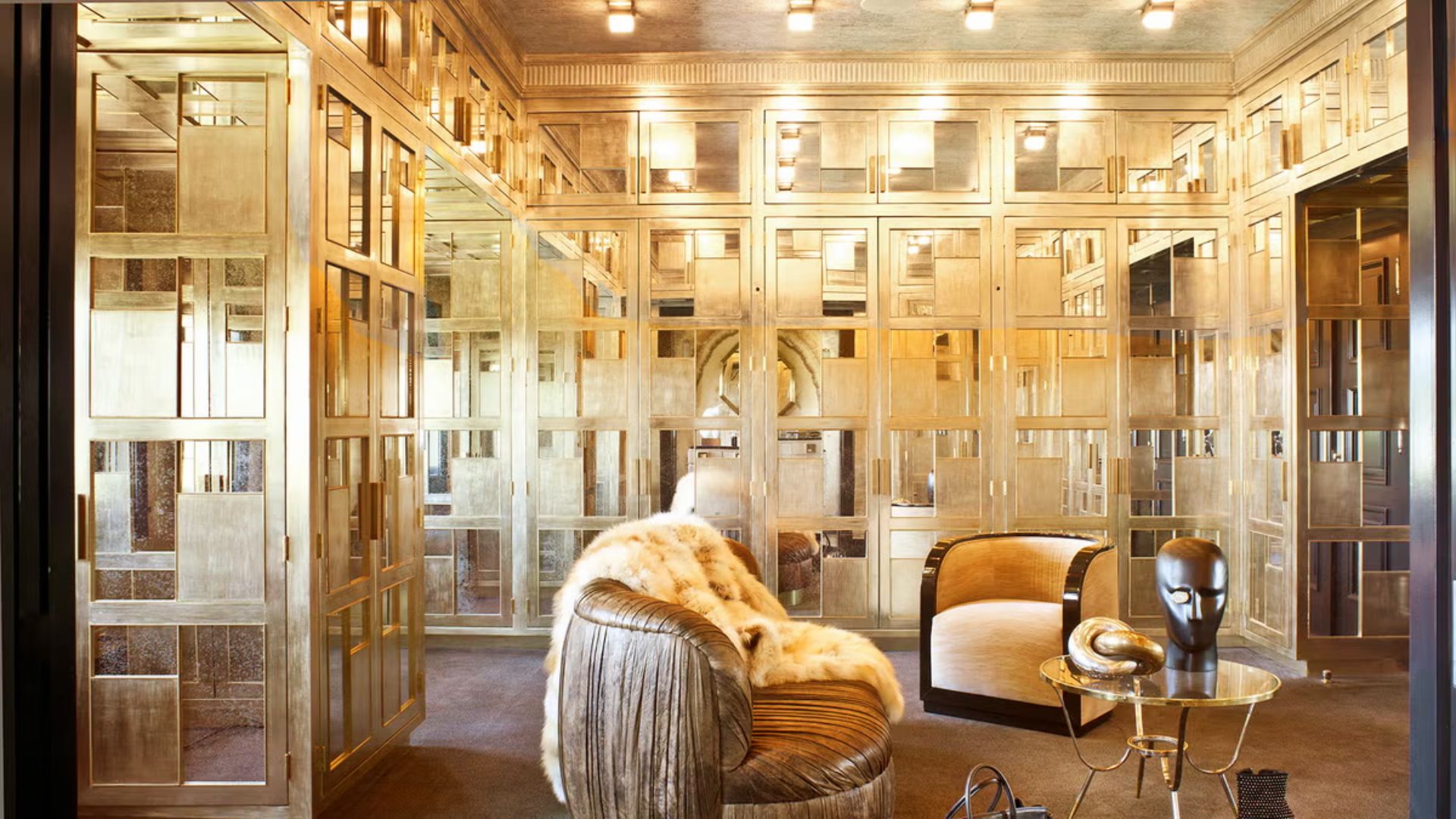 An opulent boudoir-style walk-in closet with draped curtains, round tufted daybed, and vintage-influenced vanity stations.